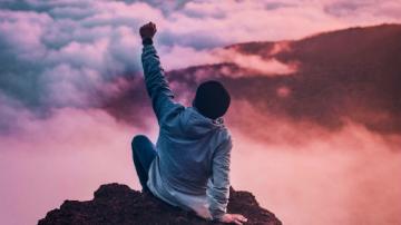 Person on top of a mountain, arm raise