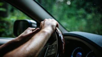 Driver's hands on the steering wheel of a car