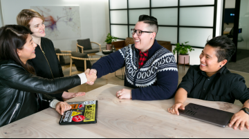 Teammates shaking hands and smiling in an office