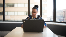 Business woman on laptop sitting in front of window